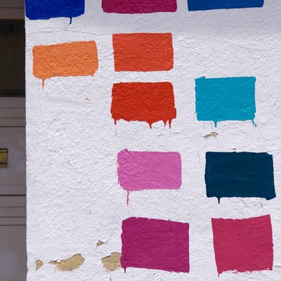 Paint samples of different bright colors on a white wall.