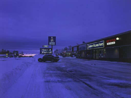 The sun begins to rise over a strip mall blanketed in snow