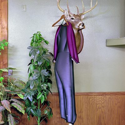 A neoprene ski jumping suit with gray body and maroon arms hangs from the antlers of a stuffed deer