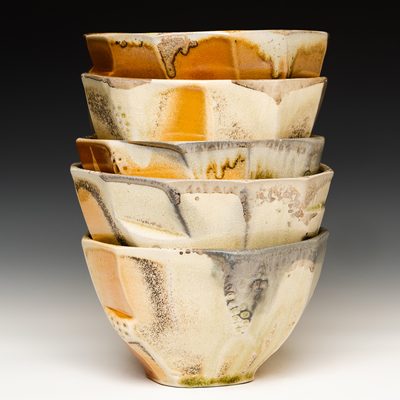 A stack of five faceted and textured woodfired bowls with white, grey, yellow, orange, and red ash deposits and flashing marks.