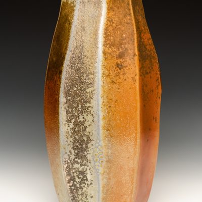 A faceted and textured woodfired vase with white, grey, yellow, orange, and red ash deposits and flashing marks.