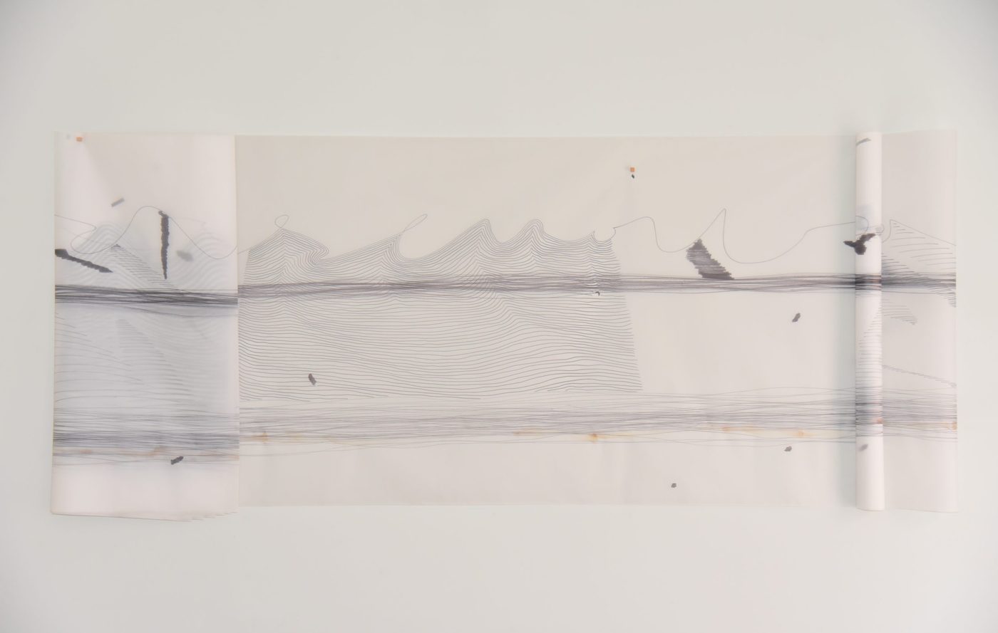 A piece of paper that is folded and tacked up onto the wall. On the paper there appears to be a landscape rendered in ink and drawn over with wavy lines. On the far right the waves are not filled in, and at the bottom there are streaks of coffee