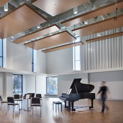Image of Shackel Hall, a Music Dept. rehearsal space, with a piano, music stands, and chairs.