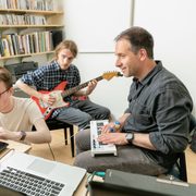 Two students and a professor compose music in an office