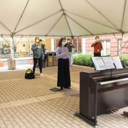 Members of the Carleton choir gathers to practice in an outdoor tent classroom in the Weitz's courtyard.