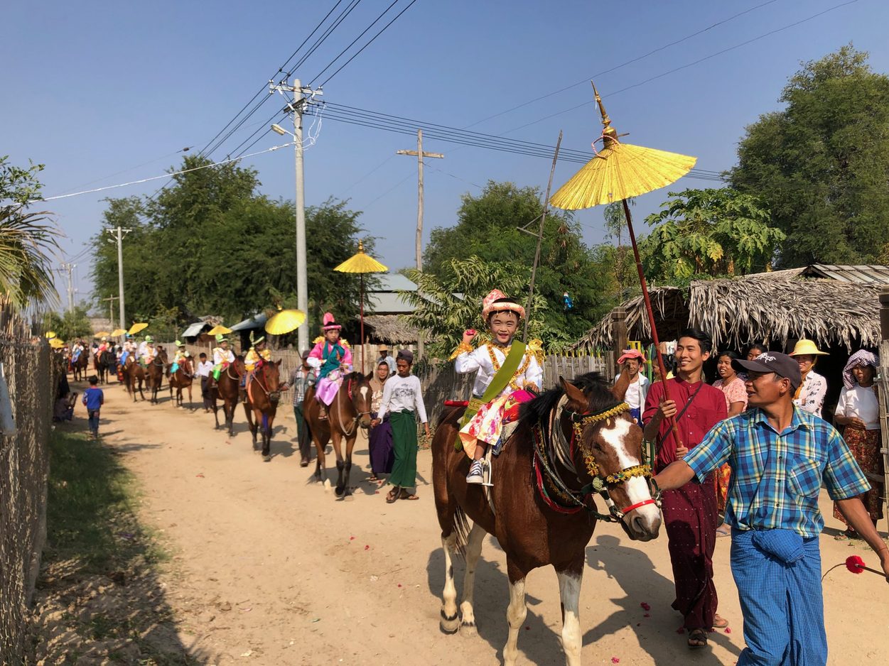 A young boy rides a horse in a village parade