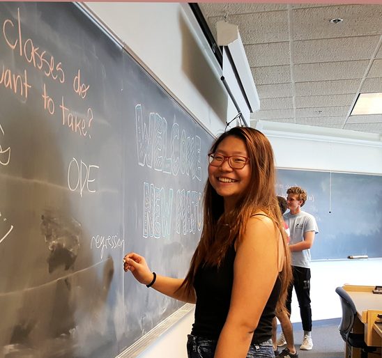 Carleton College math student solving math problem on a black board