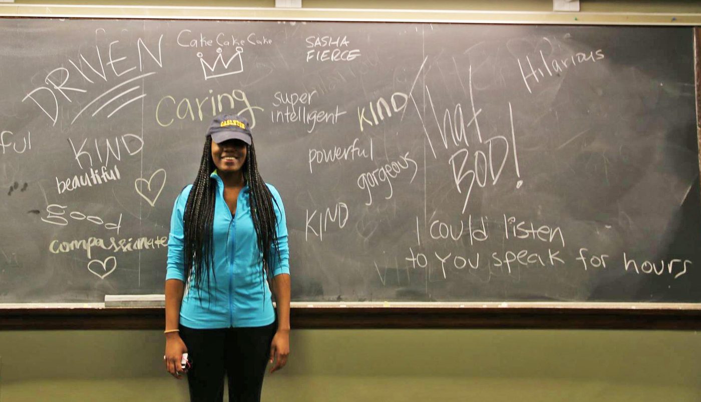 A student stands in front of a chalkboard full of affirming statements