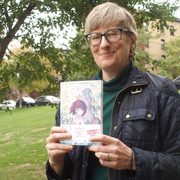 Author Marnie Jorenby holds a book with Japanese writing on the cover