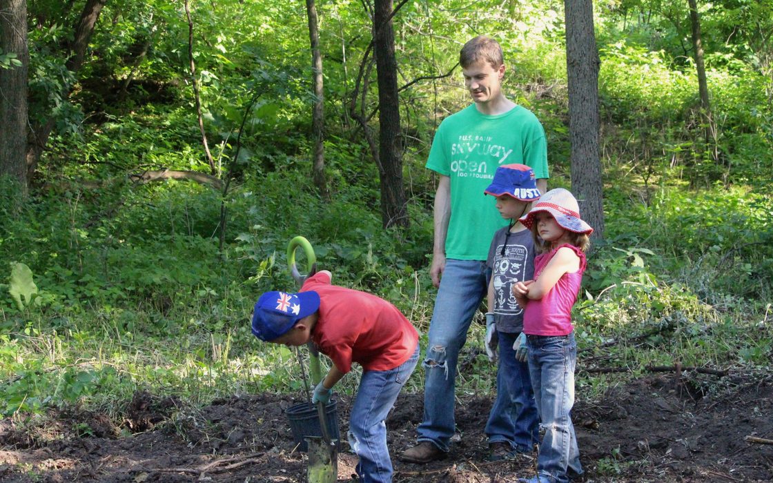 Nancy Braker leads alumni and their families in planting trees to promote the long-term ecological health of the Carleton Arboretum