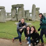 four students posing in front of stonehenge