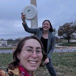 two students holding a frisbe infront of the washington monument