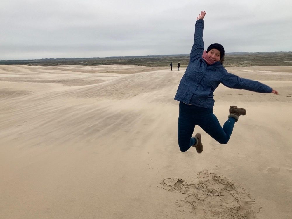student jumping in the air in sand