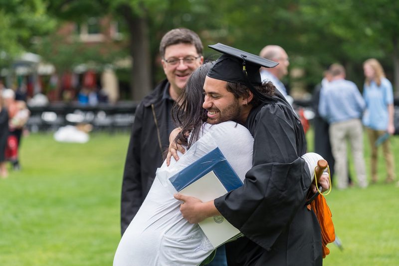 Loved ones hugging a graduating student.