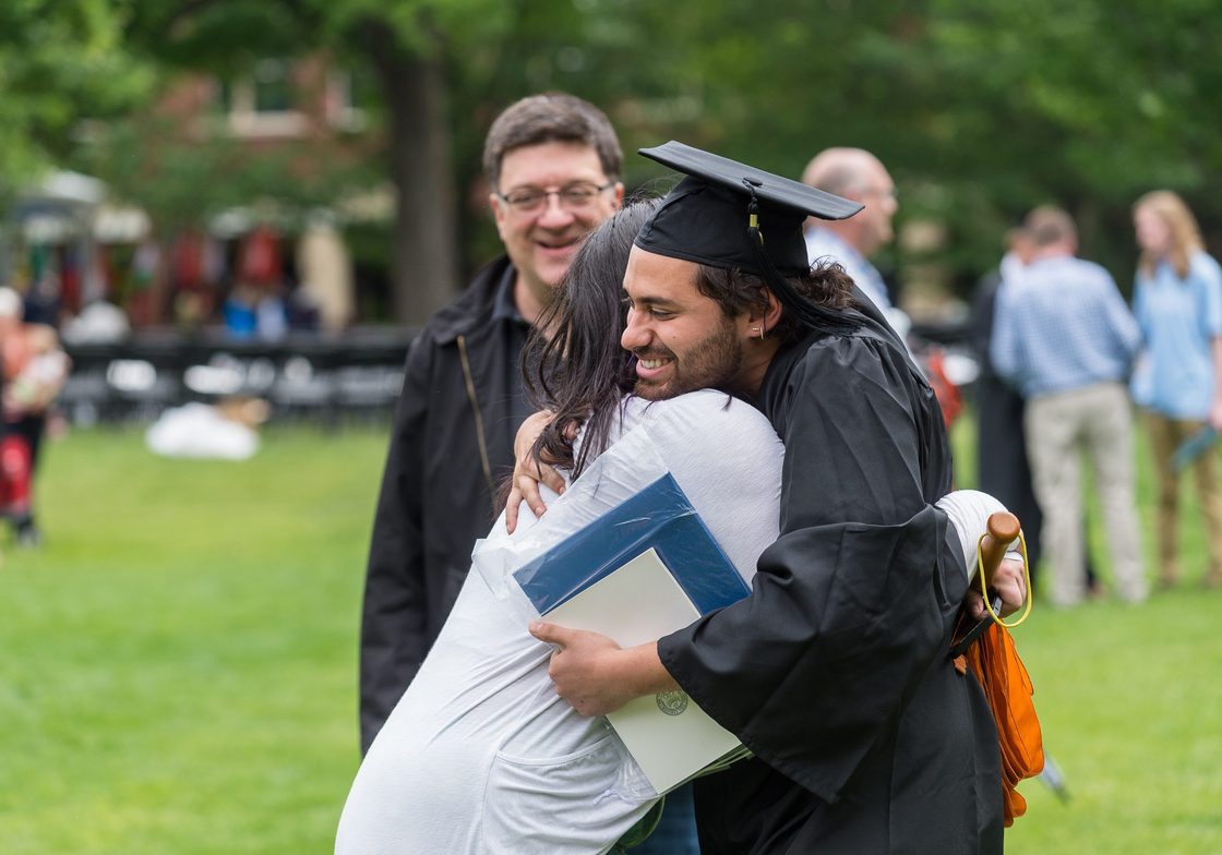 Loved ones hugging a graduating student.