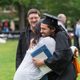 Loved ones hugging a graduating student.