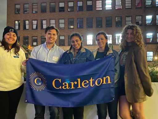 Five people hold a Carleton banner