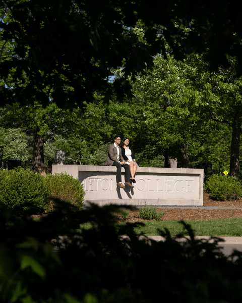 Two members of the Class of 2022 sit on the cement 