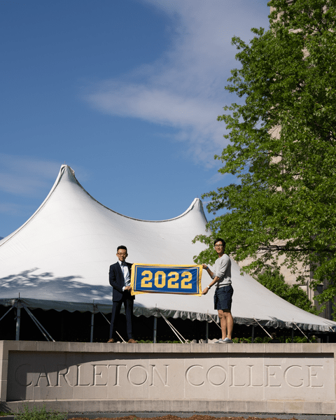 Two members of the Class of 2022 hold up their class banner while standing on the cement 