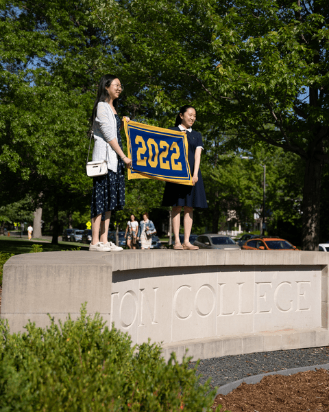 Two members of the Class of 2022 hold up their class banner while standing on the cement 