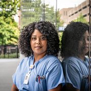 A Black woman wears surgical scrubs outdoors in an urban setting