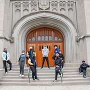 A group of Black student athletes wear Covid face coverings on the steps of Skinner chapel
