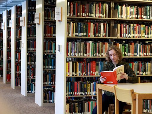 A student reading in the library stacks