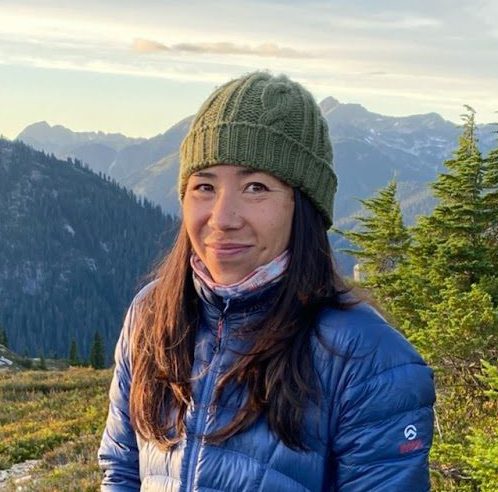 Rika Anderson smiing outdoors with mountains behind her