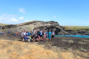 Group photo in front of rock formation in barren landscape