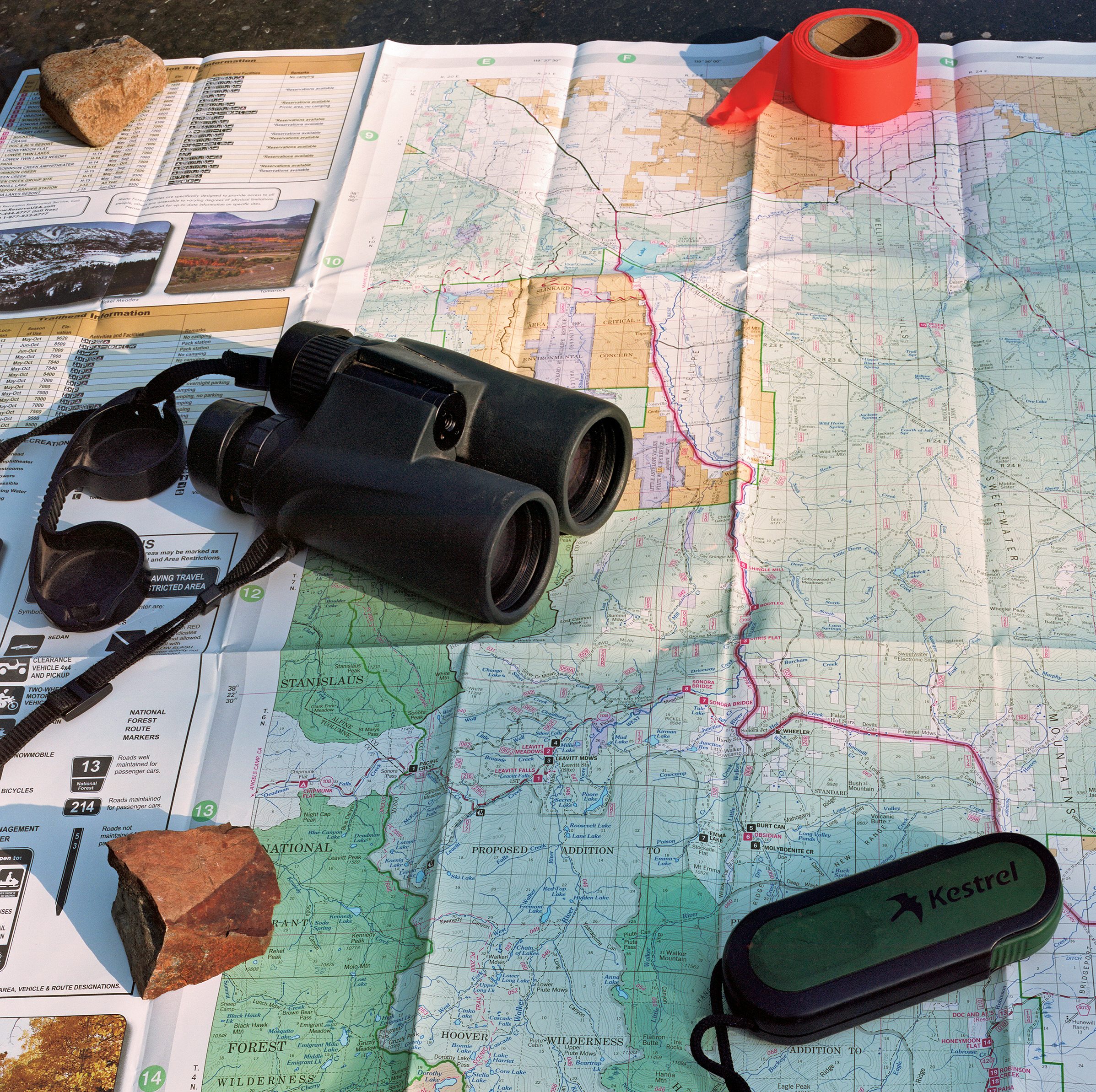 Tape, binoculars, and a kestrel tool lie across a ranger map