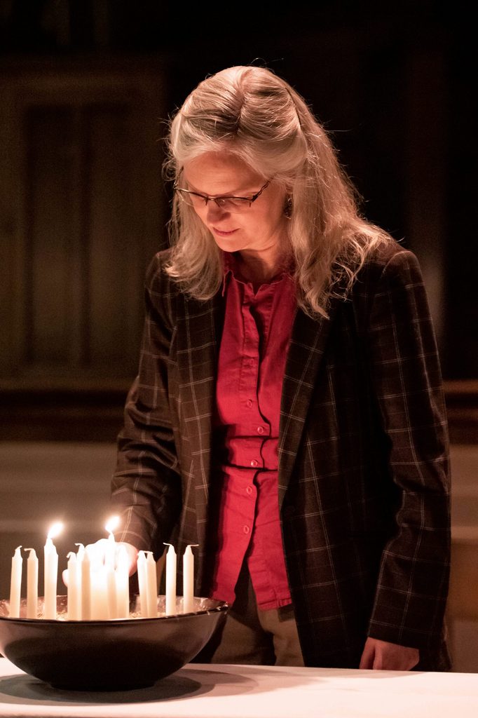 Carolyn Fure-Slocum lighting candles at an evening service in the chapel