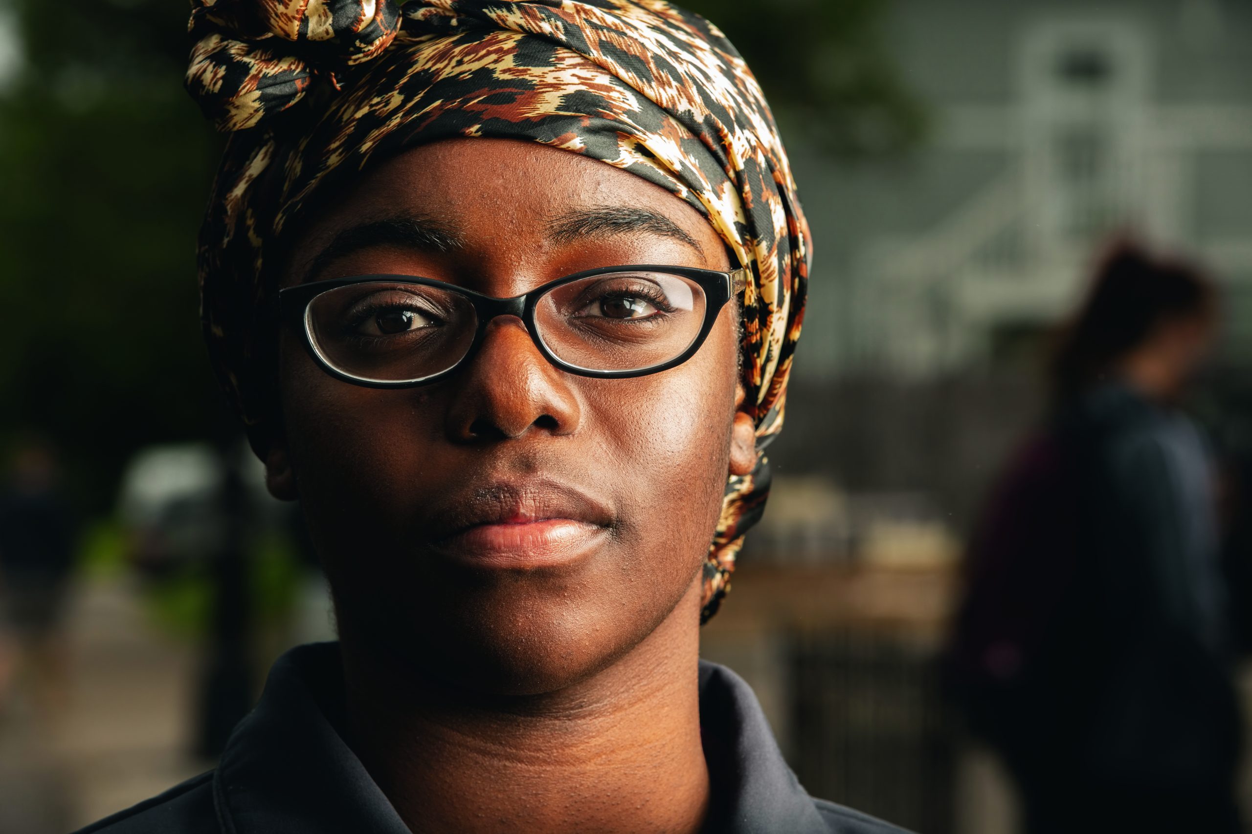 A Black woman wearing eyeglasses with a colorful scarf covering her hair