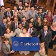 A group of wedding attendees holding a Carleton banner