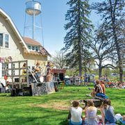 A crowd of people watch a live band on a sunny day at Carleton's Farm House