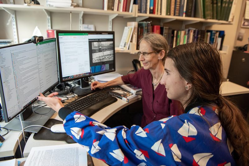 A student and professor look at a computer screen together
