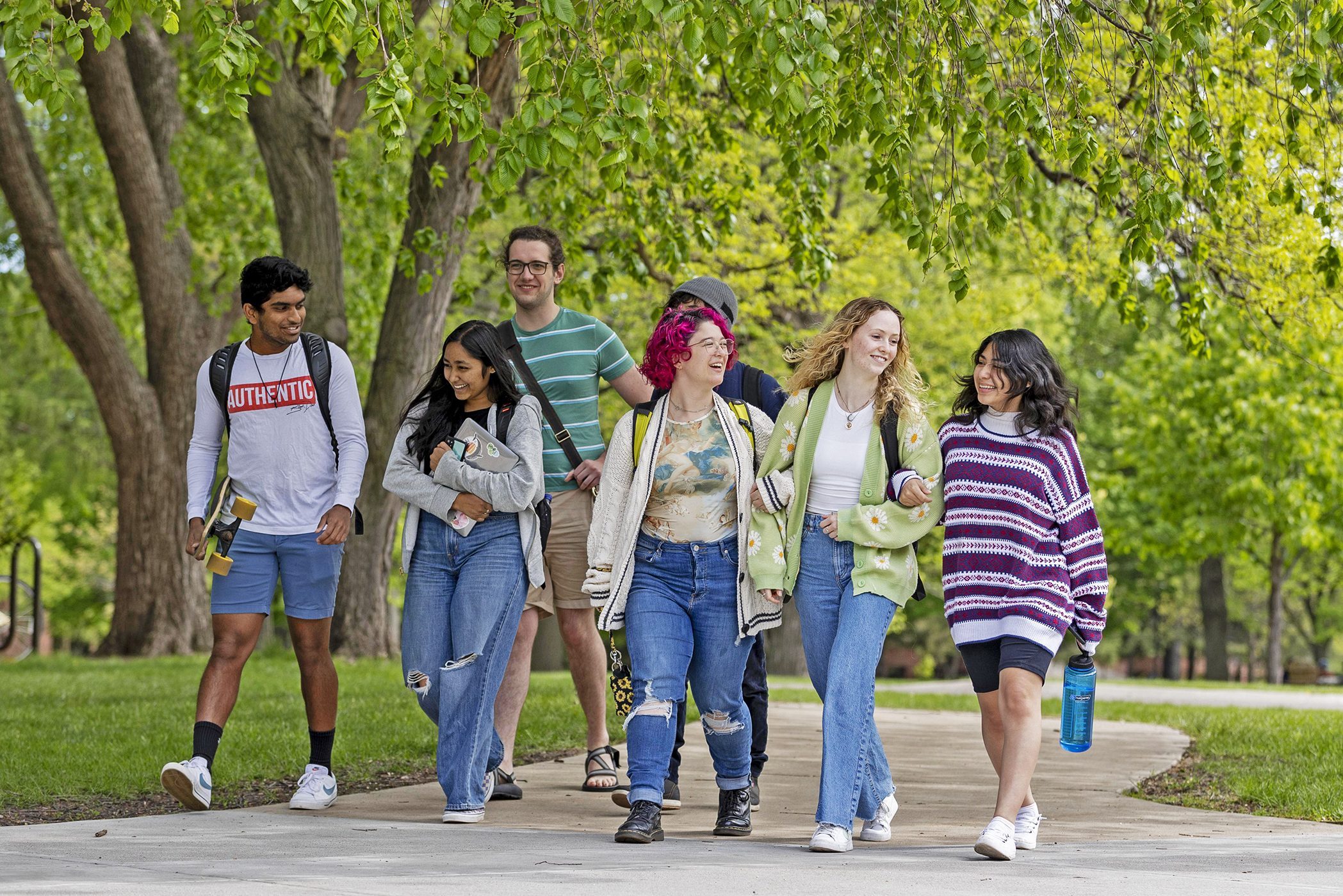 A group of happy students walk across campus on a spring day