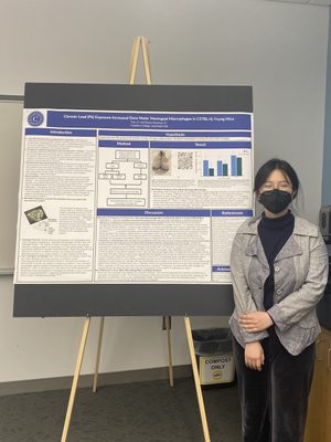 A student poses in front of an academic poster
