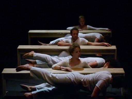 Dancers wearing white, using benches as props