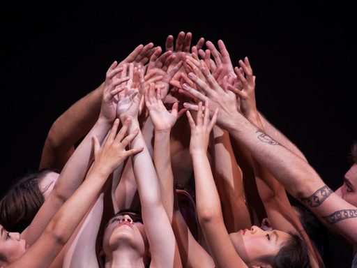 Dancers reaching their arms up together