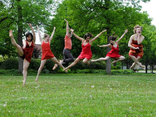 Semaphore dancers wearing red and jumping in the grass