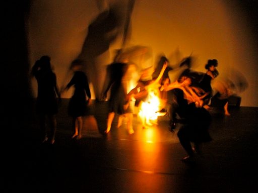 A blurry image of dancers dancing around a light