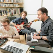 Two students and a professor compose music in an office