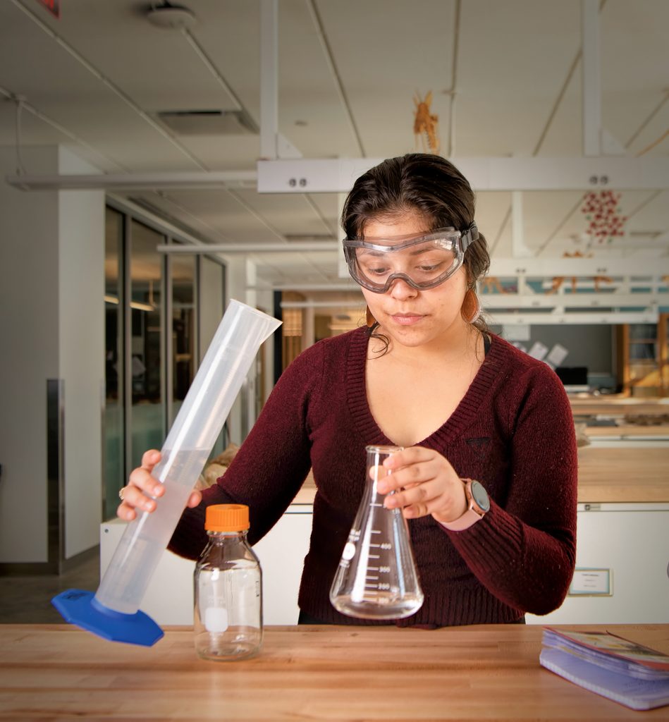 Denyse Marquez Sanchez ’21 holds a graduated cylinder and a conical flask