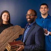 three people smile as they hold different objects from their research