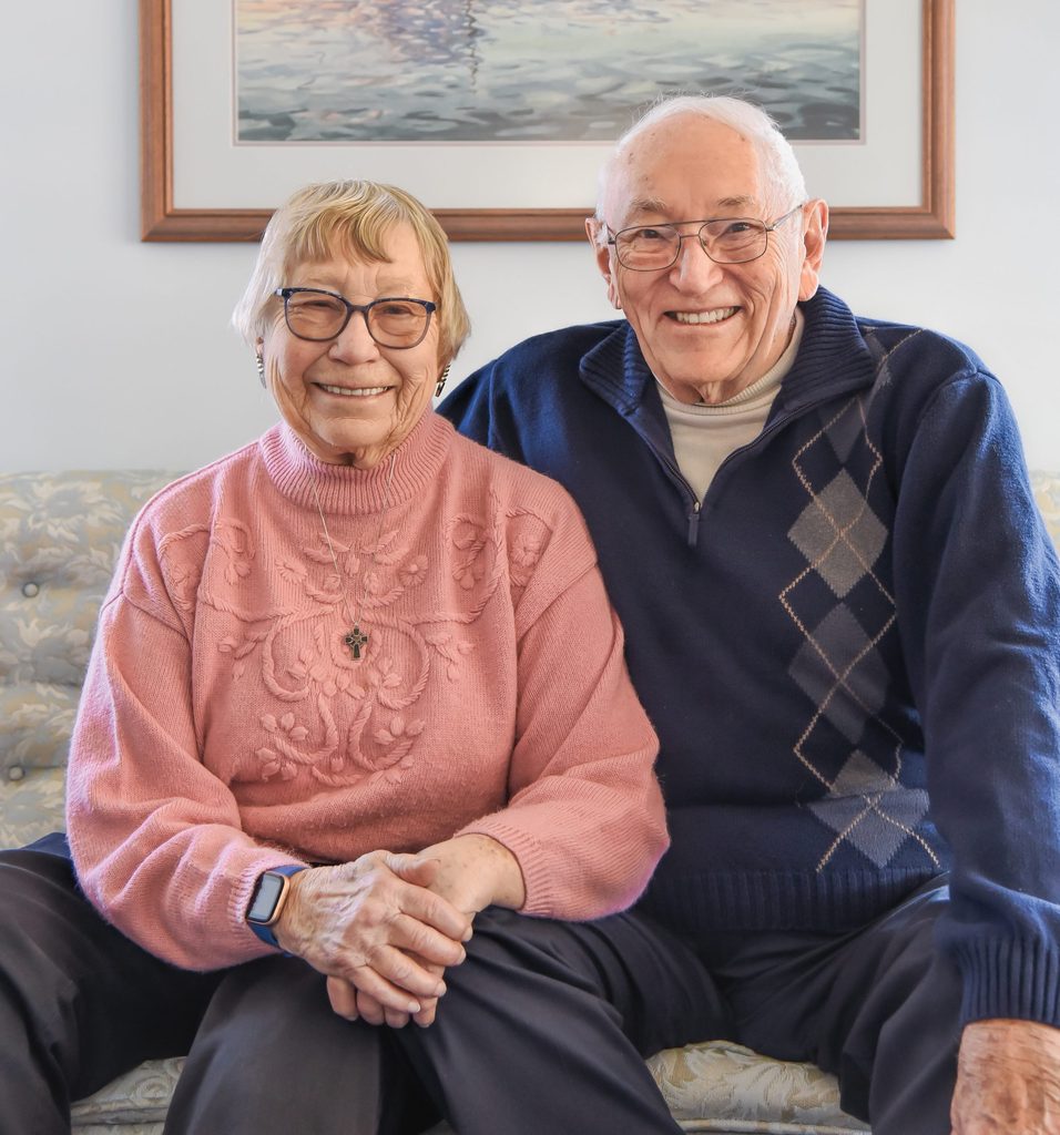 elderly couple sitting on a couch smiling
