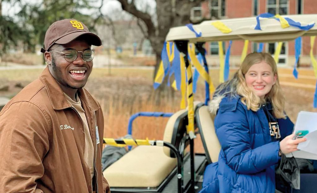 woman on a golf cart stops by student who is laughing