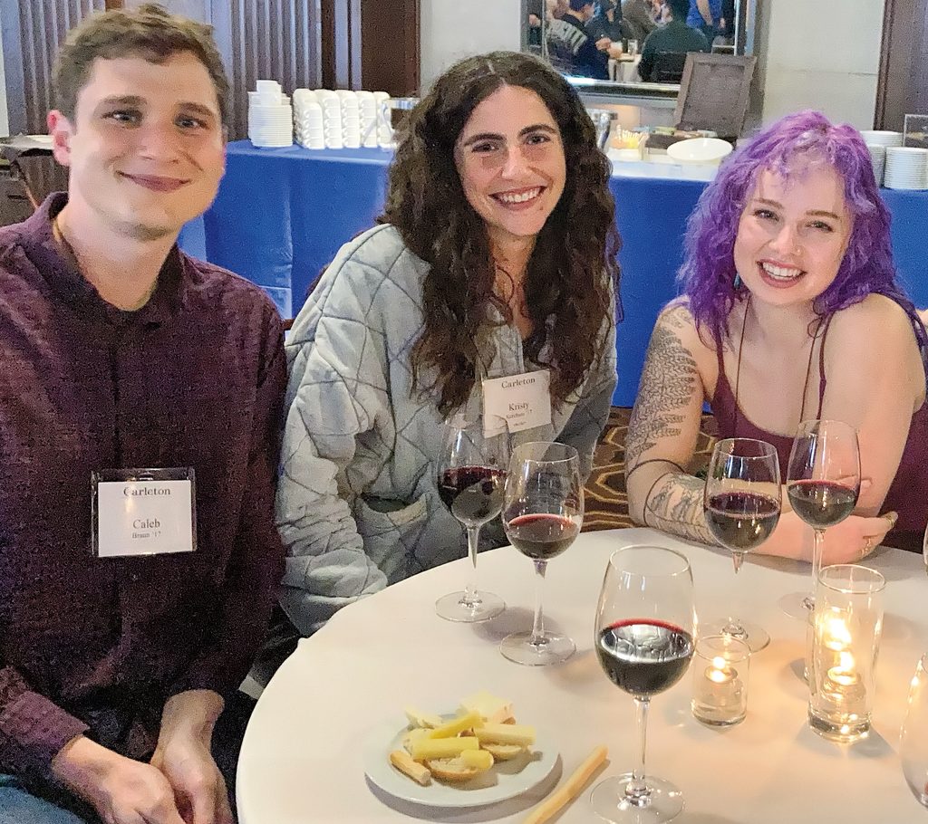three young alumni at a dinner table