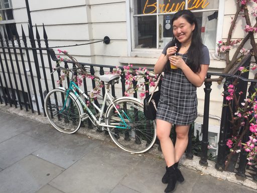 a young woman stands beside a bicycle